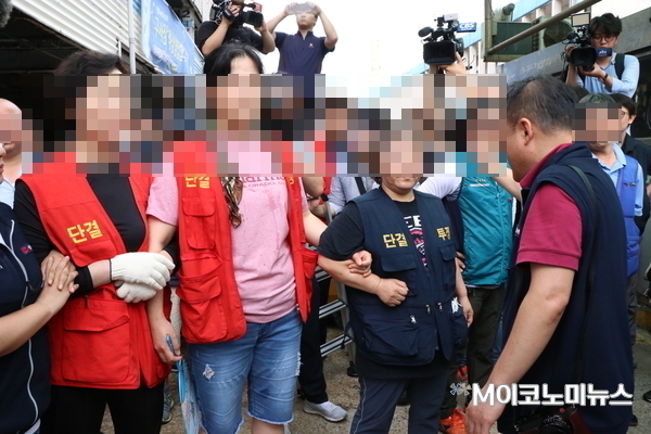 서로의 팔짱을 끼고 집행관들의 진입을 막는 구시장 상인들 <사진 : 박종호 기자>