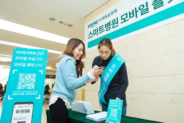 방문객을 대상으로 도우미가 이대목동병원 스마트 앱 설치를 도와주고 있다.