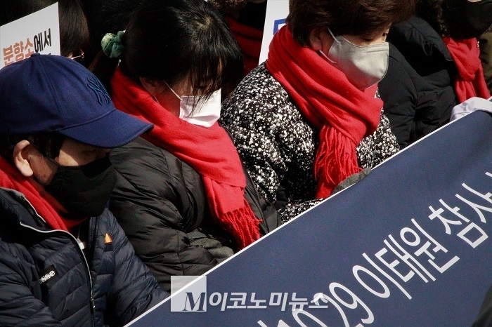 이태원 참사 유가족이 15일 오후 1시 서울도서관 앞 분향소에서 기자회견을 열고 있다. 앞쪽에 앉은 유가족이 침울한 표정으로 플랜카드를 보고 있다. <사진: 김종현 기자>