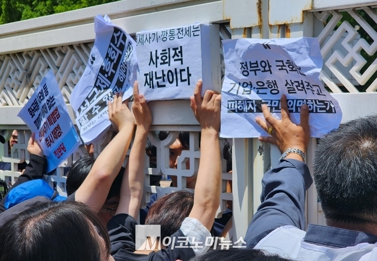 지난 5월 23일 전세사기 피해자들이 국회에 민원을 제기하기 위해 진입을 시도하다 저지당하자 정문 앞에서 '전세사기는 사회적 재난이다' 문구가 적힌 종이를 흔들고 있다. <M이코노미뉴스 DB>