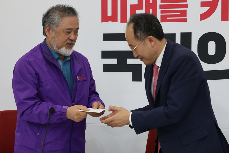 국민의힘 추경호 원내대표가 22일 오후 서울 여의도 국회에서 이태원 참사 유족들과 가진 면담에서 이정민 10.29 이태원참사 유가족협의회 위원장(왼쪽)으로부터 2주기 추모제 초청장을 받고 있다. 사진=연합뉴스