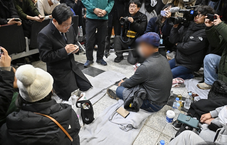 더불어민주당 이재명 대표가 29일 오후 전남 무안국제공항에서 제주항공 여객기 폭발사고 탑승객 가족들을 위로하며 요청사항을 메모하고 있다. (연합뉴스)