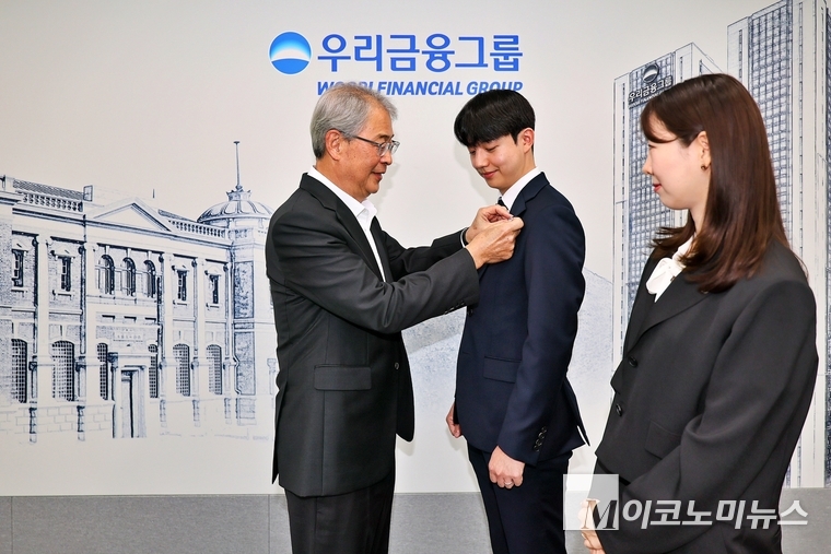 우리금융그룹 임종룡 회장이 그룹의 새 가족이 된 동양생명·ABL생명 직원에게 디지털 선도의 의미가 담긴 새로운 그룹 보조휘장을 달아주고 있다. 사진=우리은행