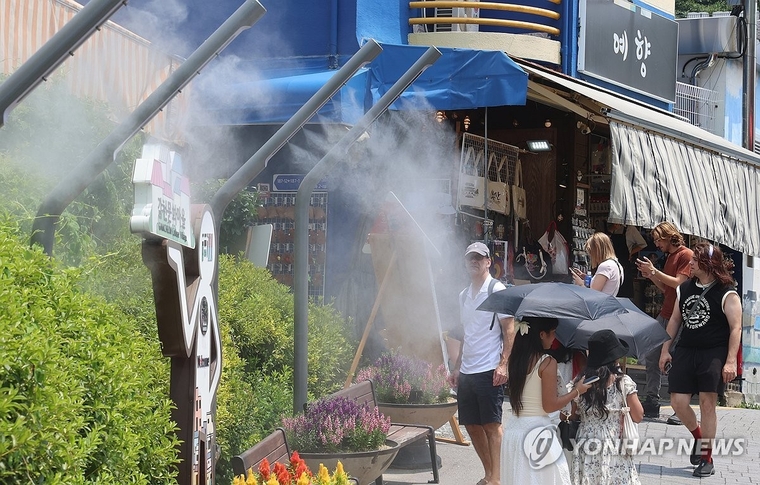 연일 열대야와 폭염이 이어지는 가운데 8일 오후 부산 사하구 감천문화마을 입구에 물안개를 분사하는 쿨링 포그가 설치돼 외국인 관광객들이 더위를 식히고 있다. 사진=연합뉴스