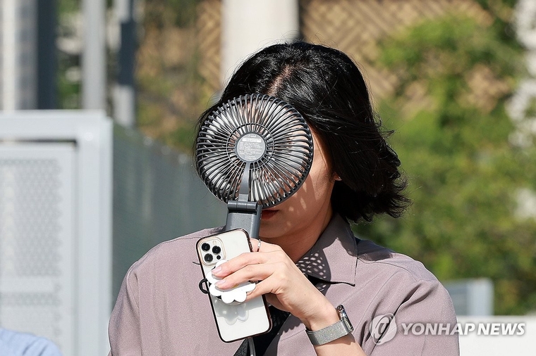 한 시민이 더위를 피하기 위해 휴대용 선풍기를 사용하며 이동하고 있다. 사진=연합뉴스