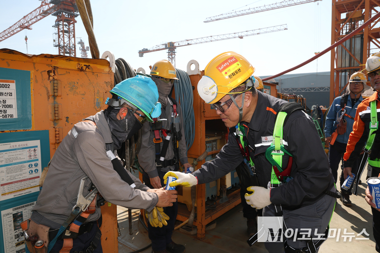 한화오션 김희철 대표이사(오른쪽)가 건조 중인 LNG선박 위에서 근로자들에게 시원한 음료를 건네고 있다. 사진=한화오션 
