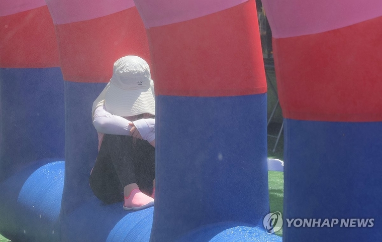 폭염의 날씨가 계속되는 26일 서울 성북구 숭덕초등학교에서 열린 제9회 성북문화바캉스에서 한 어린이가 그늘에 앉아 더위를 피하고 있다. 사진=연합뉴스