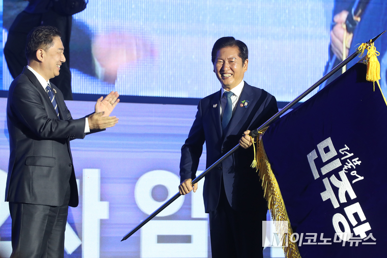 정청래 신임 당대표가 2일 고양시 일산 킨텍스 제2전시장에서 차기 당대표를 선출하는 전국임시당원대회에 김병기 더불어민주당 당대표 직무대행 겸 원내대표로부터 당기를 받고 있다. 사진=최동환 기자