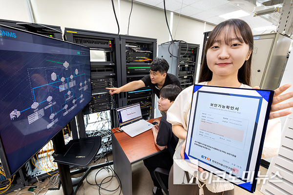 KT와 코위버 직원이 양자키분배 기술 적용 장비를 점검하며 보안 인증서를 소개하고 있다. 사진=KT
