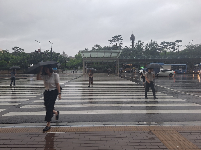 서울 도심에 비가 내리고 있는 가운데, 시민들이 우산을 쓰고 이동하고 있다. 
